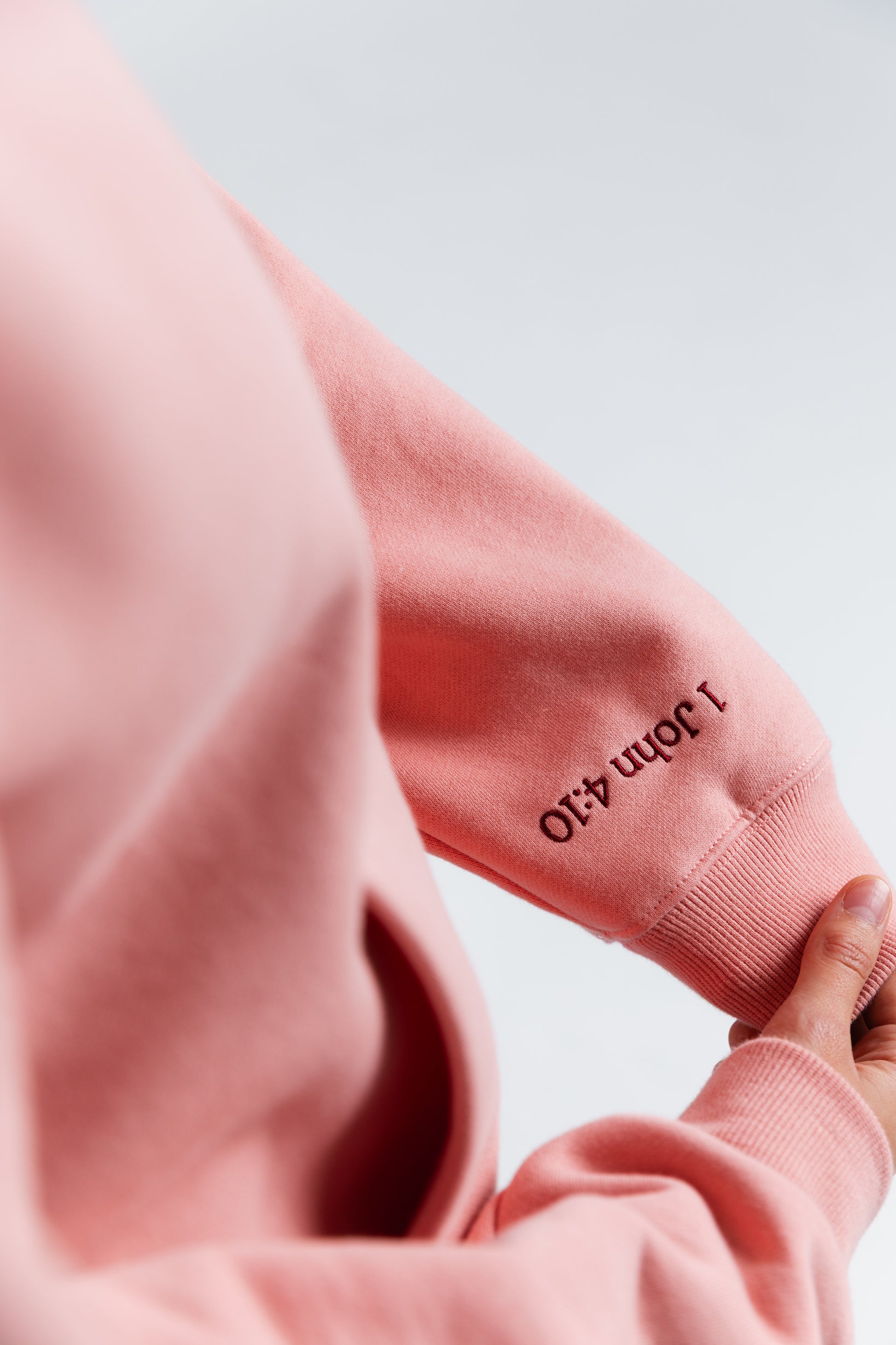 Close-up of a pink hoodie with text on a light blue background#color_pink
