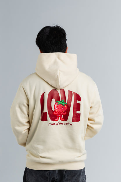 Person wearing a cream hoodie with red text and graphics on the back, on a plain background#color_cream