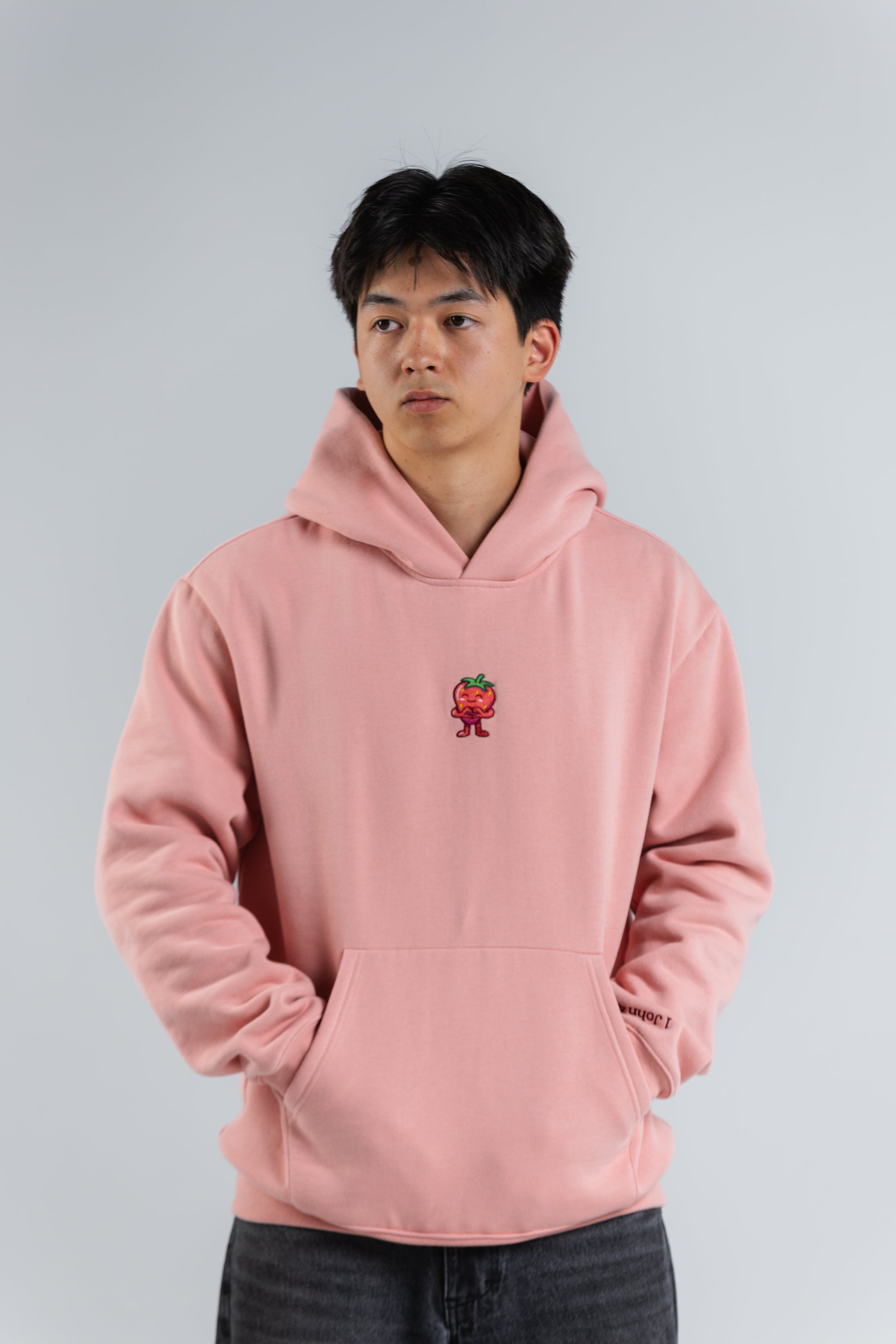 Person wearing a pink hoodie with a small logo on a plain background#color_pink