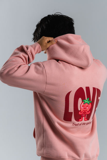 Person wearing a pink hoodie with a red 'LOVE' graphic on the back against a gray background#color_pink